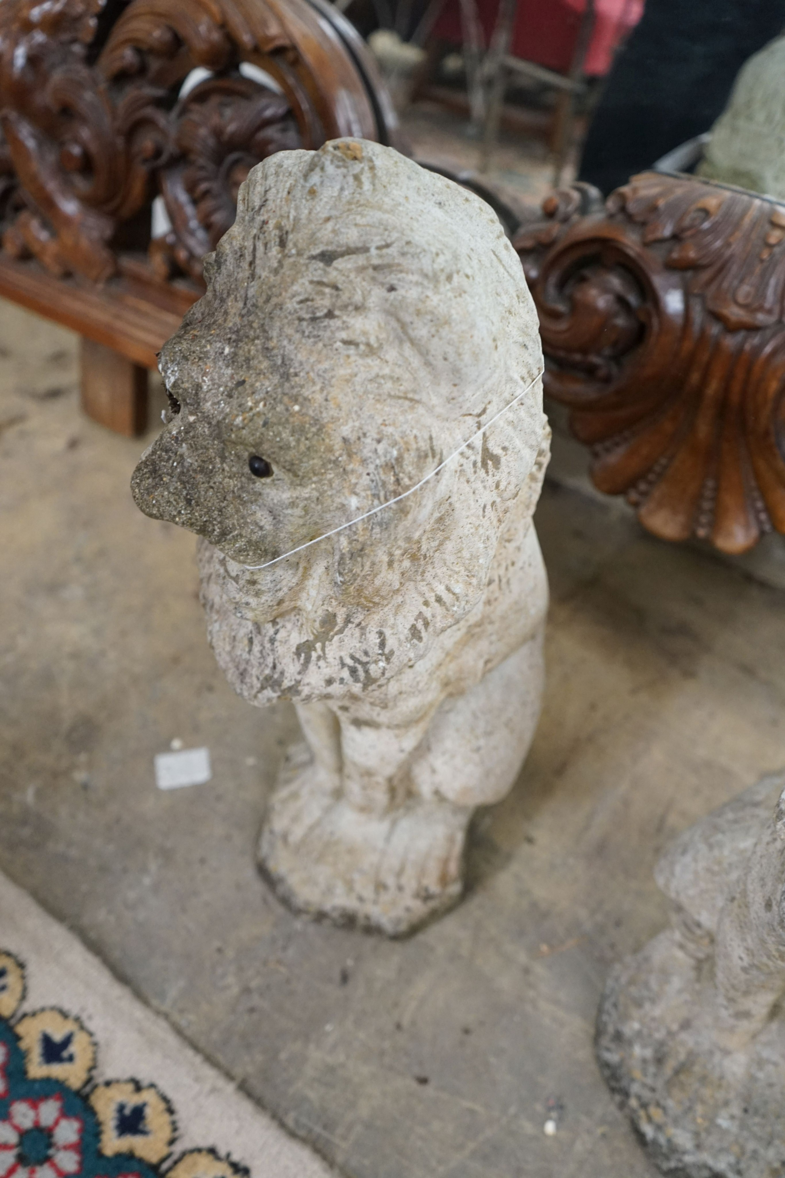 A pair of reconstituted stone seated lion garden ornaments, height 50cm